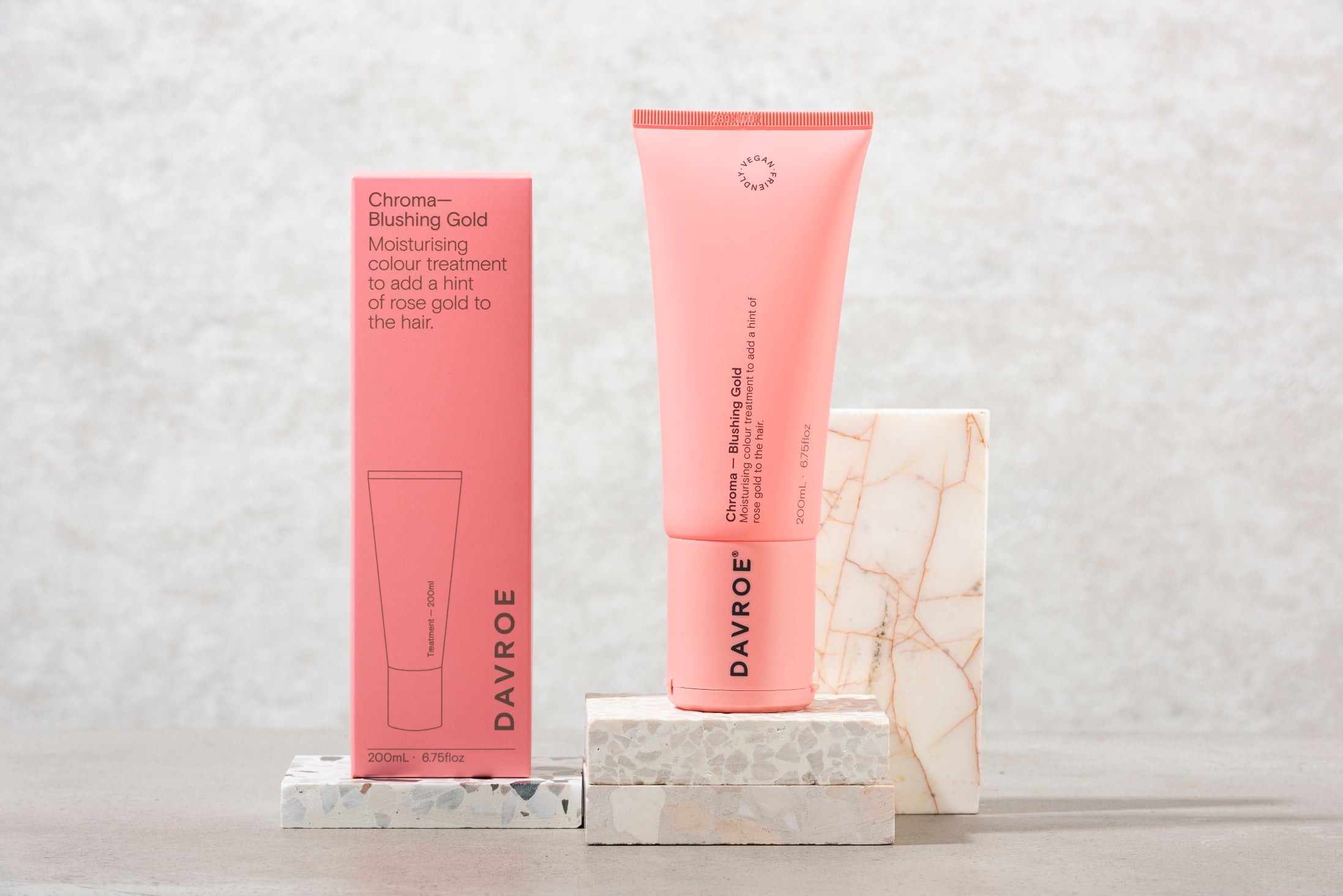 Pink Davroe hair product and packaging on a marble surface with a light gray background