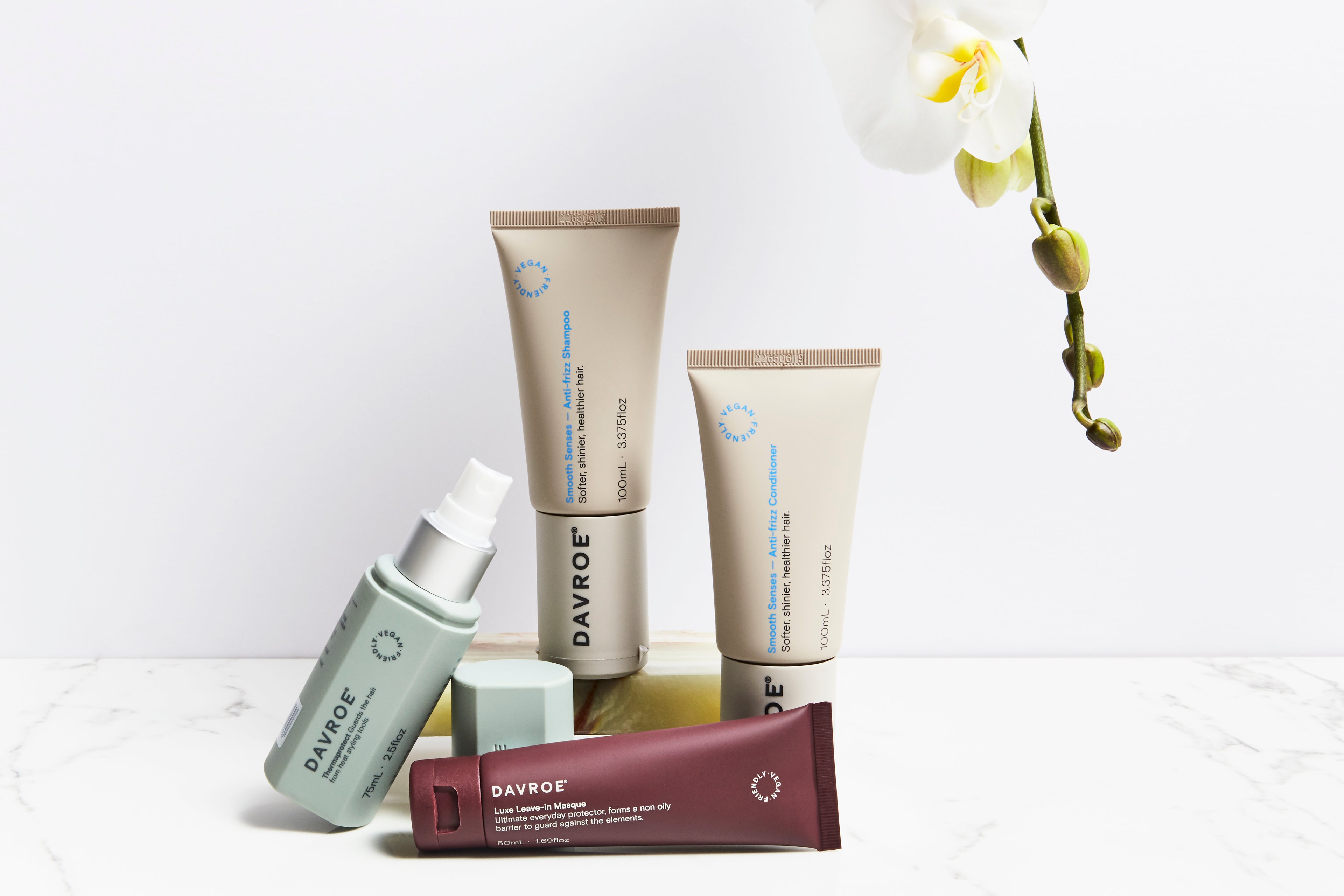 Set of Davroe skincare products on a white background with an orchid.